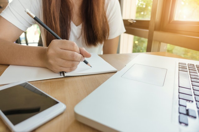 anak perempuan dengan baju putih sedang belajar didepan laptop